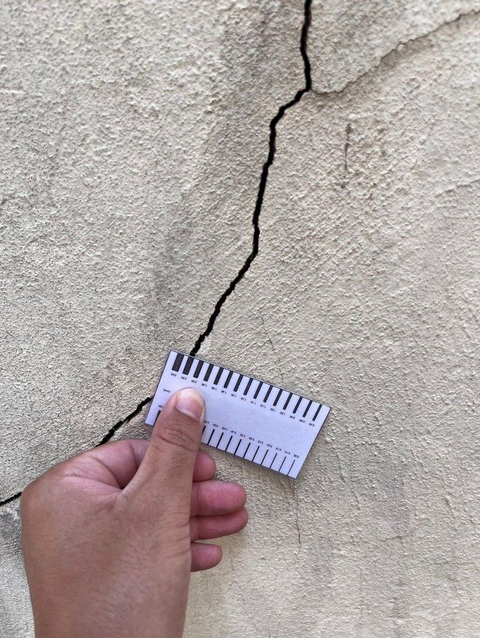 Medição de fissura com fissurômetro durante inspeção estrutural